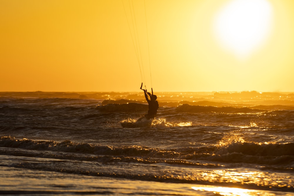 silhouette of person surfing on sea during sunset