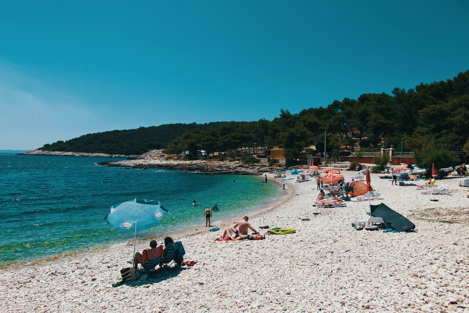 A quiet pebble beach with a wooded headland
