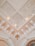 An ornate ceiling with intricate architectural details including moldings, decorative patterns, and recessed lighting. The design features symmetrical geometric shapes and relief decorations, conveying a sense of elegance and classical architecture.