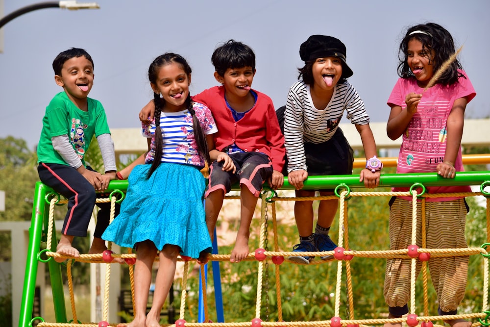 children standing on green metal fence during daytime