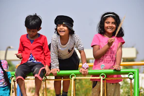 Smiling children playing together on outdoor playground equipment under a clear sky