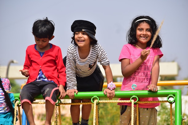 A father and his two sons playing in a park, laughing and enjoying a sunny day.