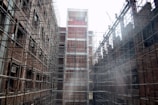 Mid-construction phase showing brick walls rising with scaffolding around.