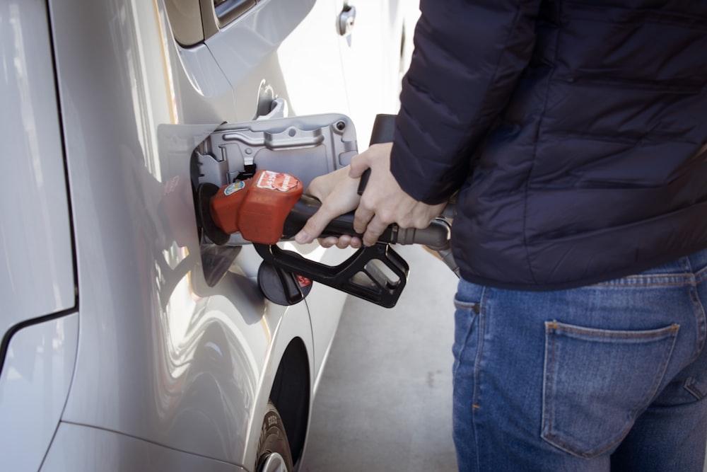 um homem bombeando gasolina em seu carro em um posto de gasolina