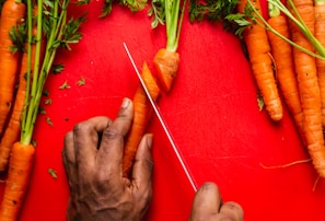 A modern, ergonomic vegetable peeler lying next to freshly cut carrots.