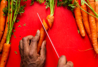 A multi-functional vegetable peeler with ergonomic handle peeling a bright orange carrot.