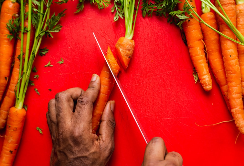 a person cutting carrots with a pair of scissors