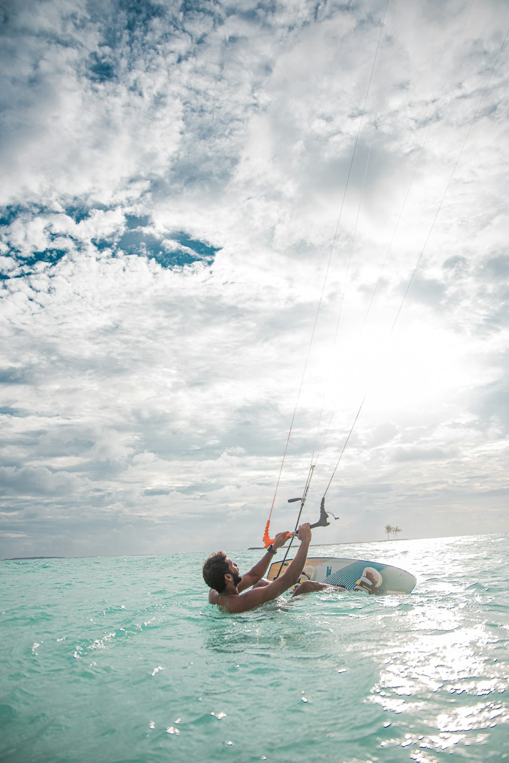 a man in the ocean holding onto a kite