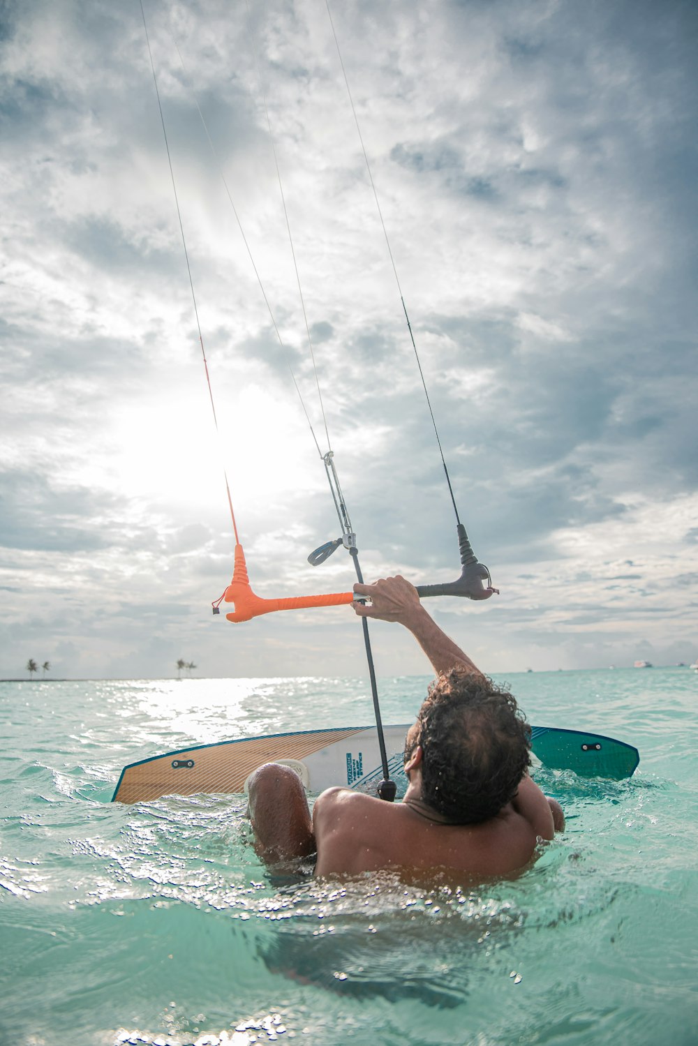 Um homem está na água com uma prancha de surf e uma pipa