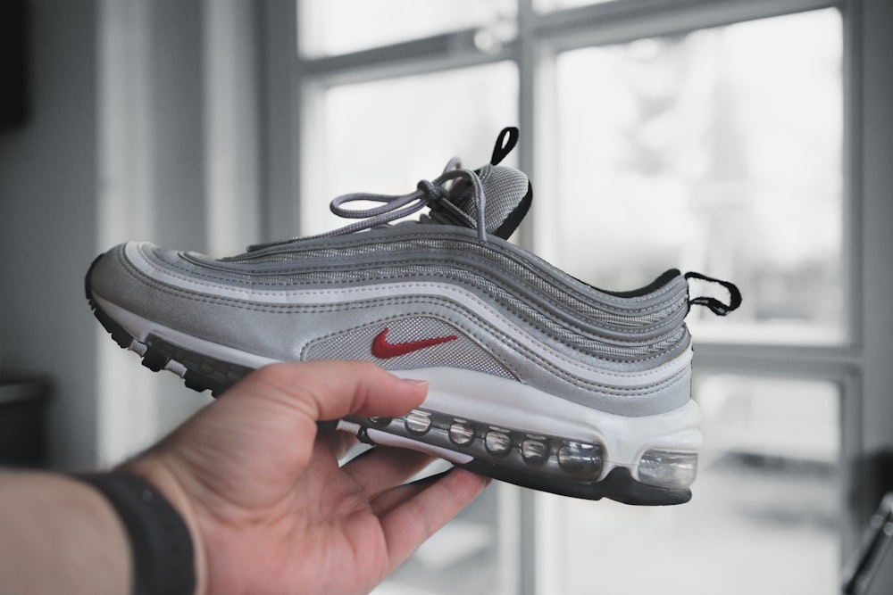 person holding gray and white nike athletic shoe