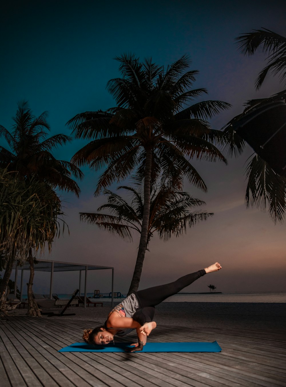 a woman doing a handstand on a mat in front of a palm tree