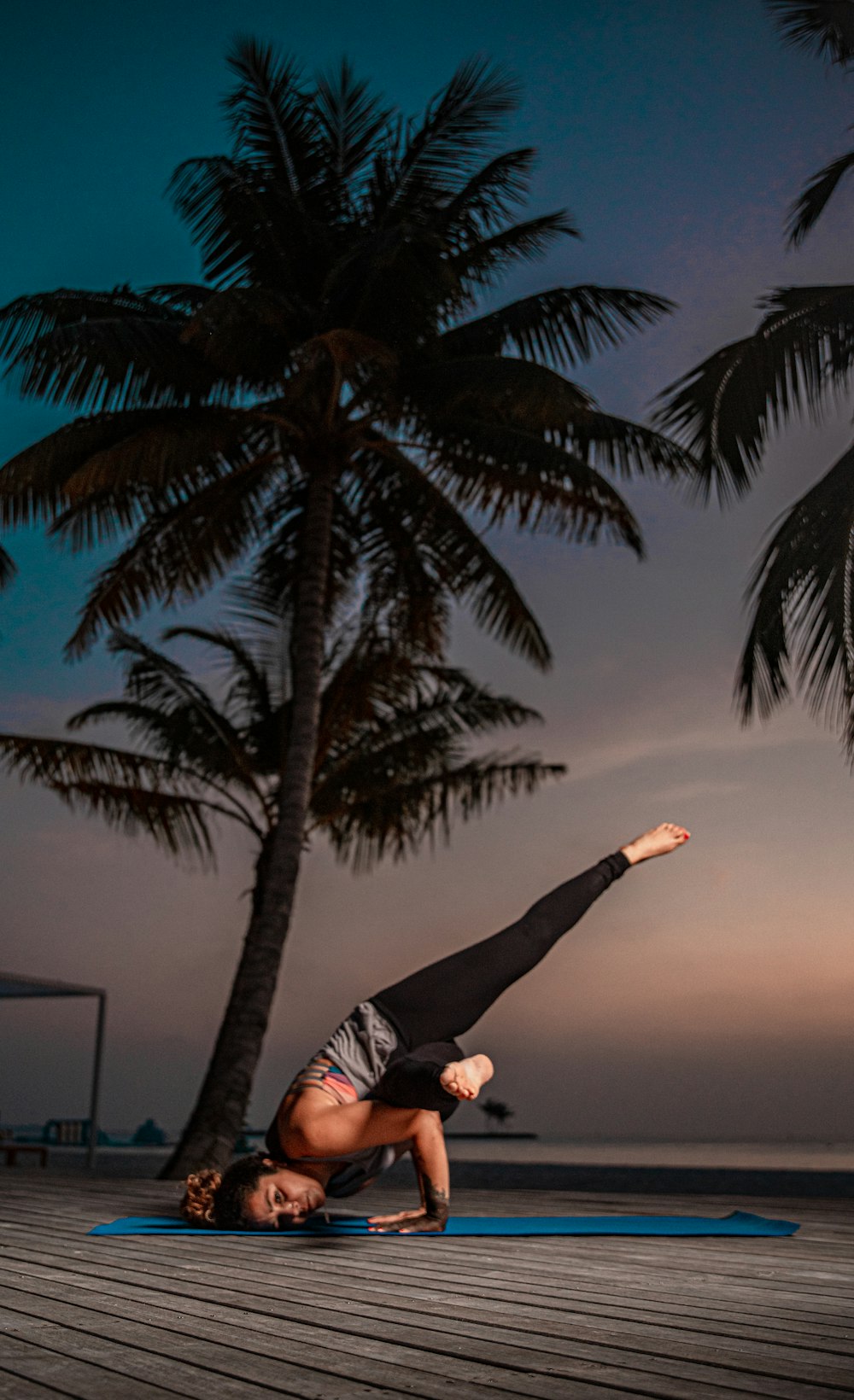 a woman doing a handstand on a blue mat