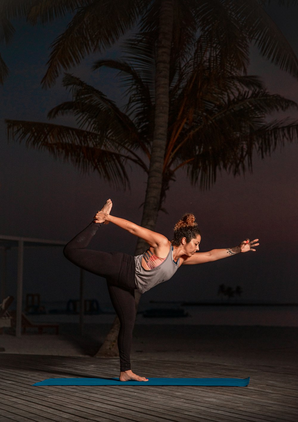 Una mujer haciendo una pose de yoga en una colchoneta azul