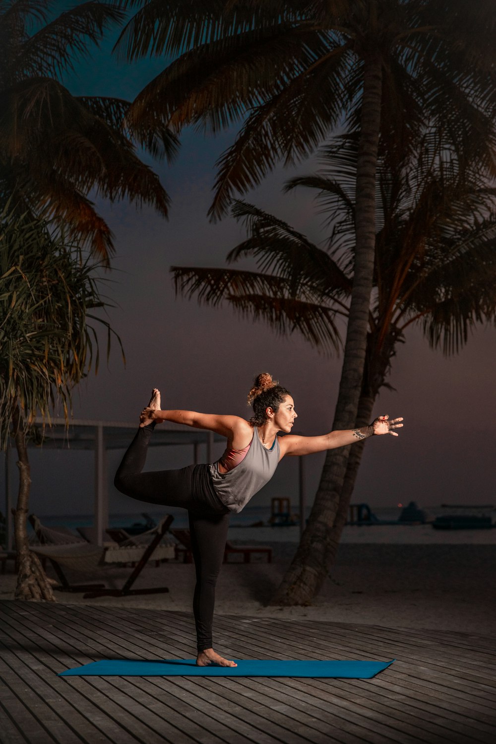 Una mujer haciendo yoga en una colchoneta frente a palmeras