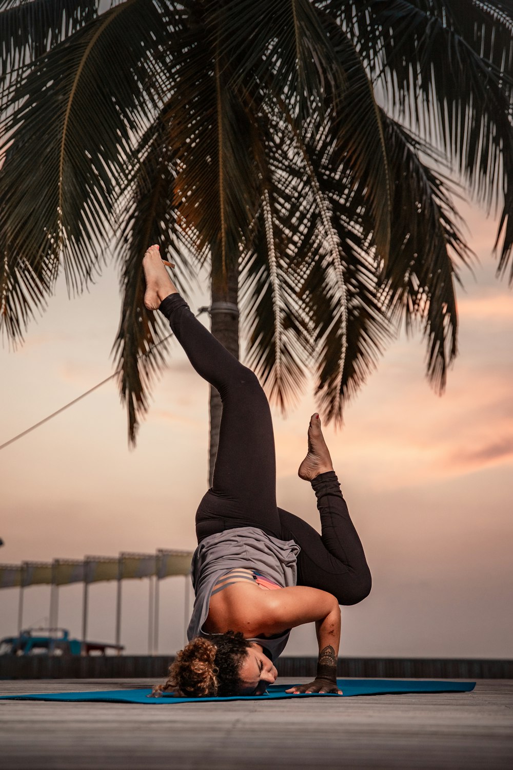 a woman doing a handstand on a surfboard under a palm tree