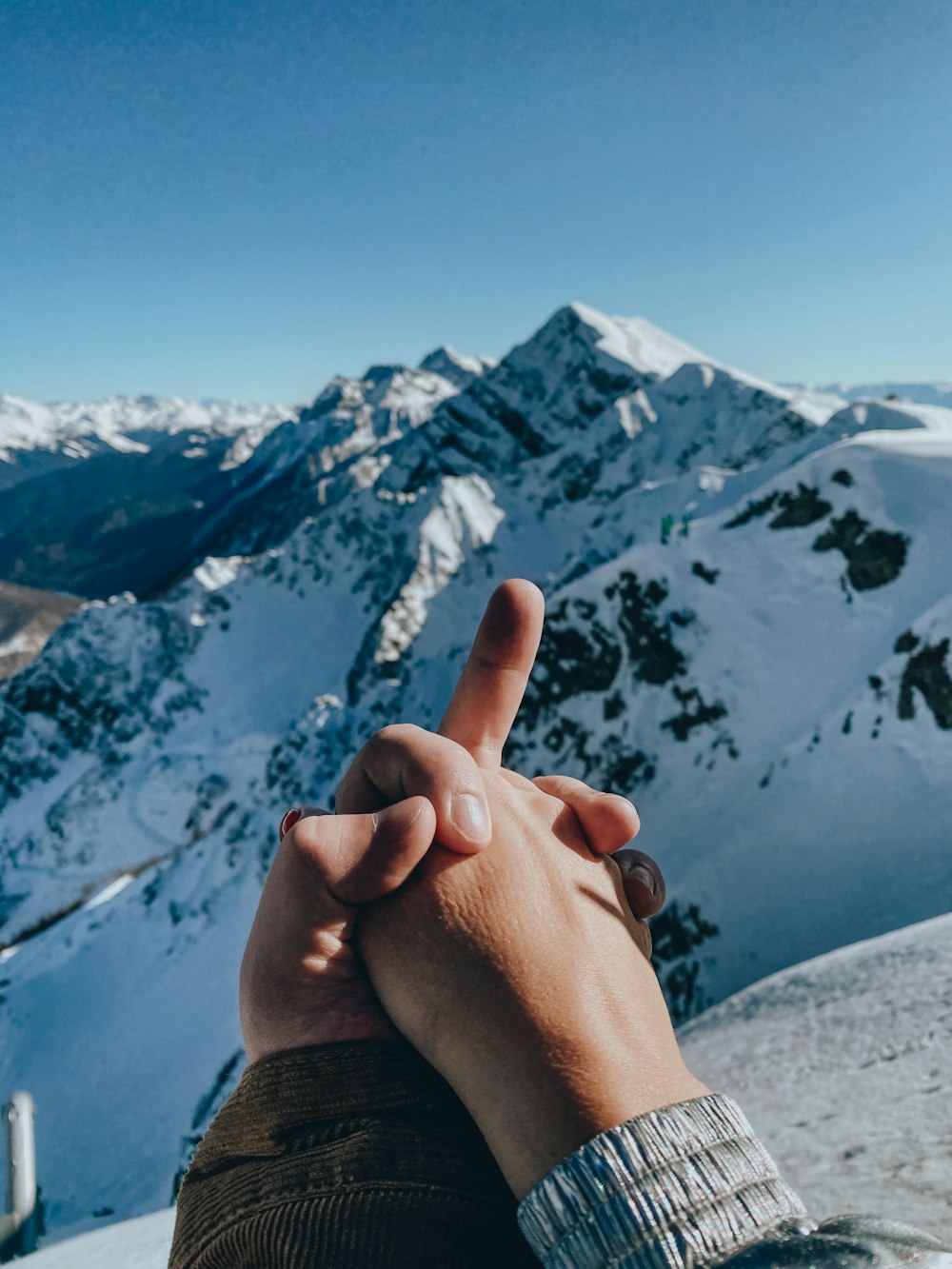 person in brown sweater showing middle finger