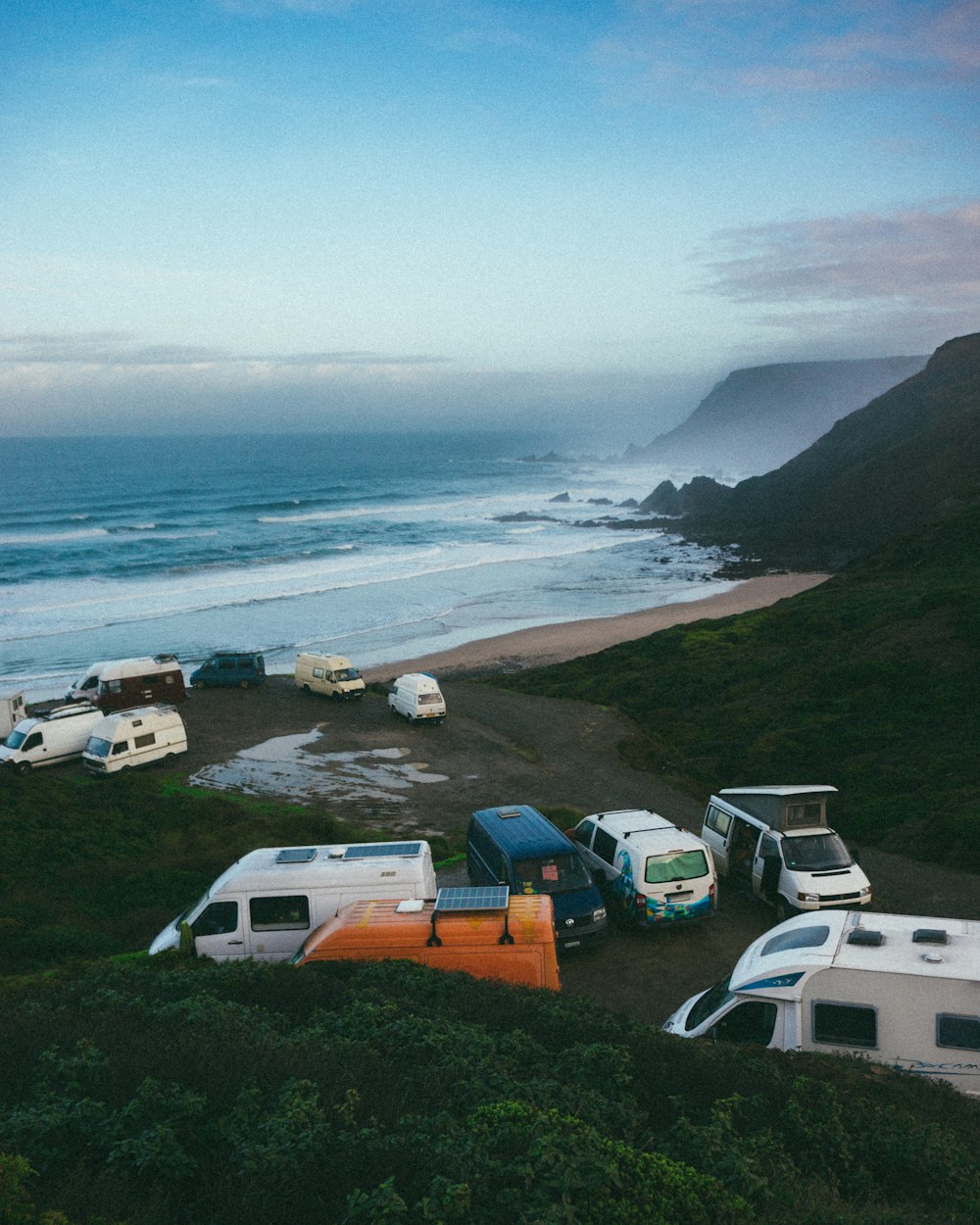 a group of campers parked on a beach next to the ocean