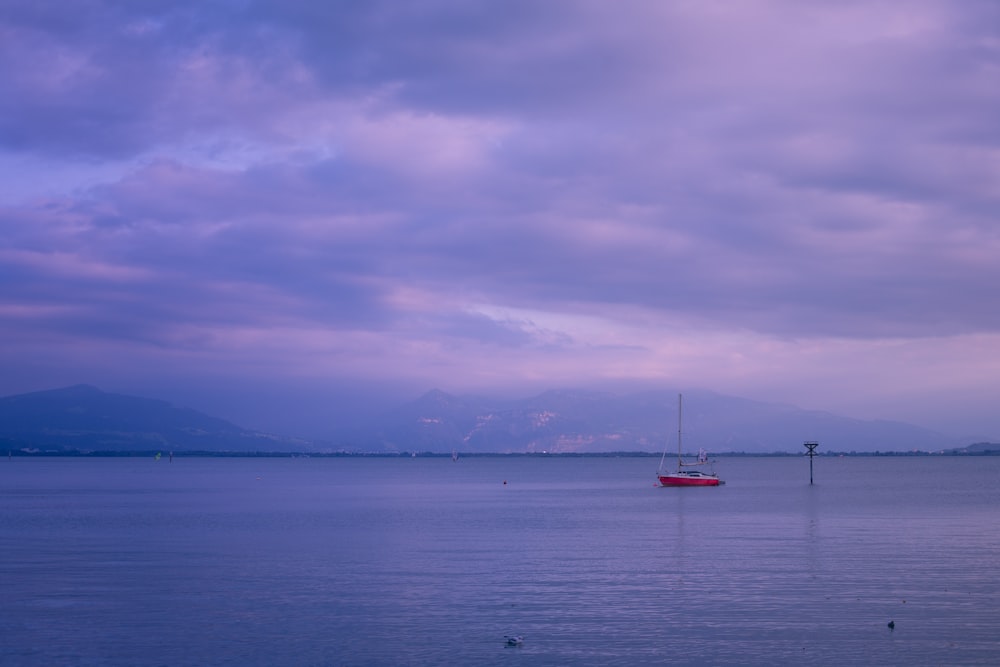 a red boat floating on top of a large body of water