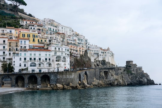 white concrete building near body of water during daytime in Amalfi Coast Italy