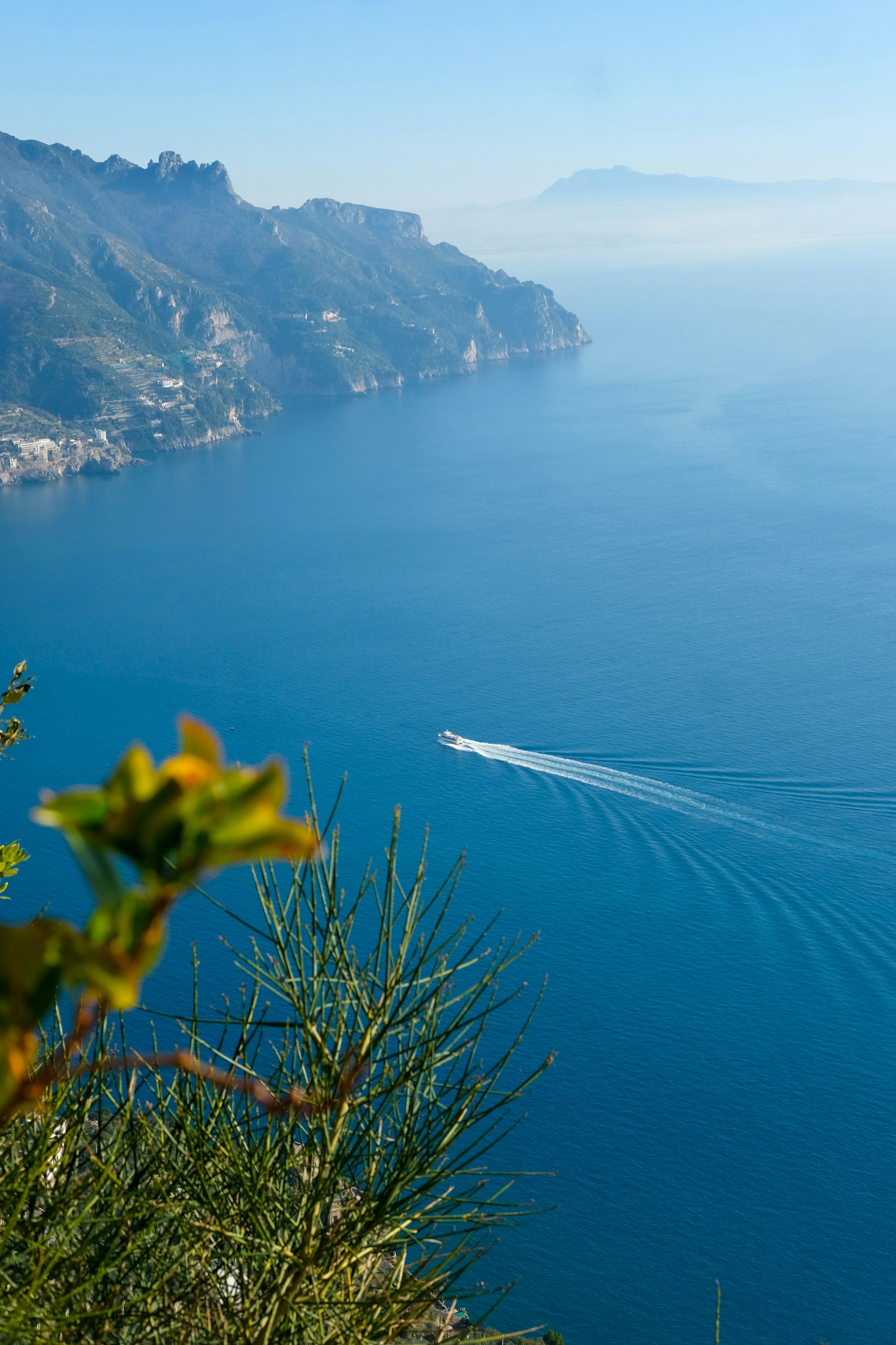 white and black boat on sea near mountain during daytime