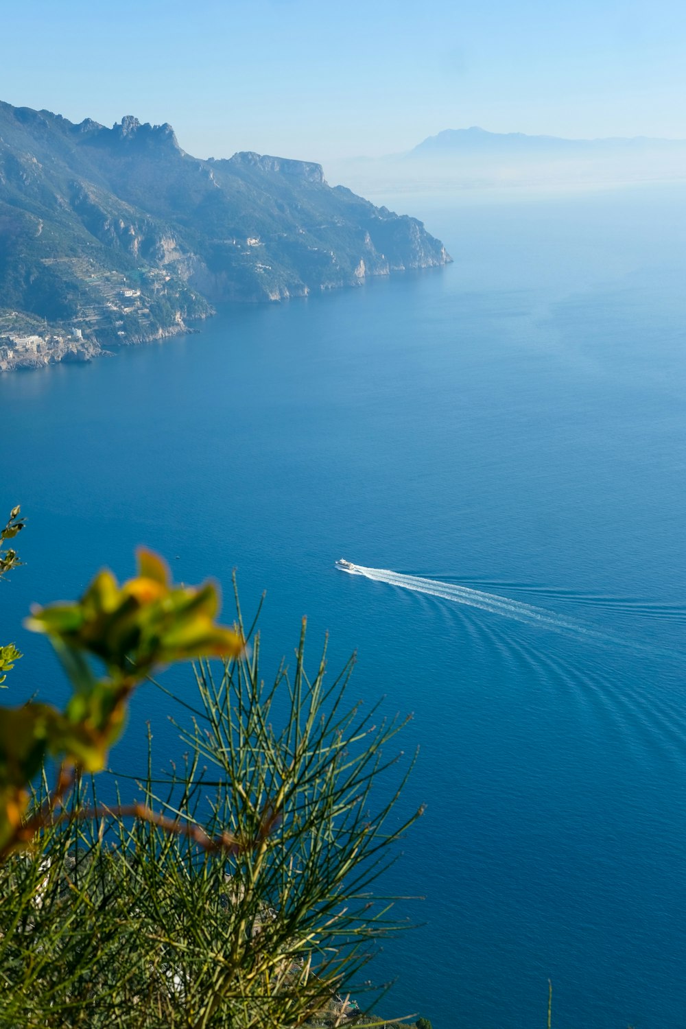 white and black boat on sea near mountain during daytime