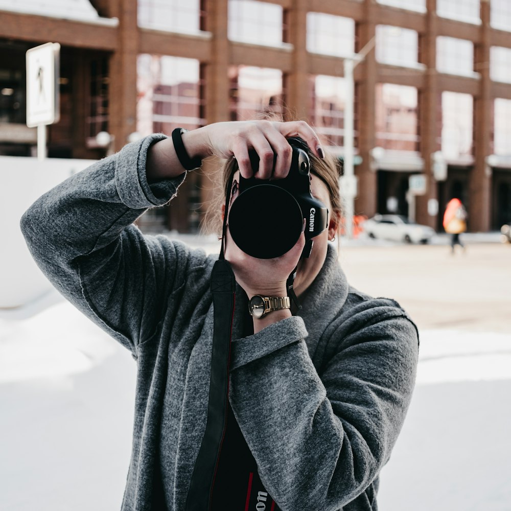 woman in gray coat holding black sunglasses