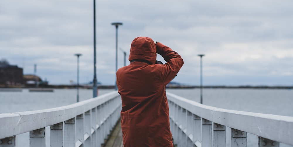 uomo in felpa rossa con cappuccio che si copre il viso con le mani