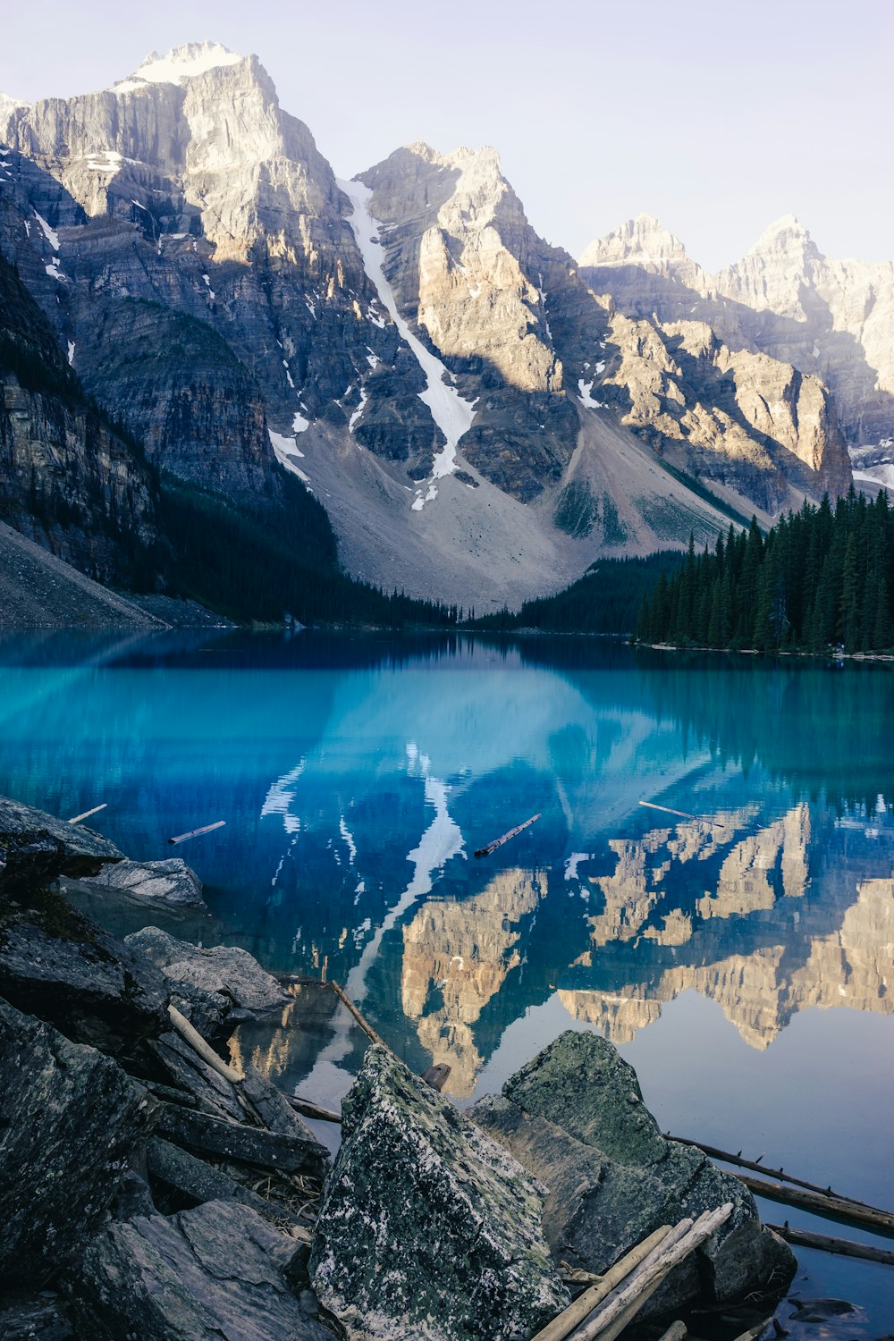 lac entouré d’arbres verts et de montagnes enneigées pendant la journée