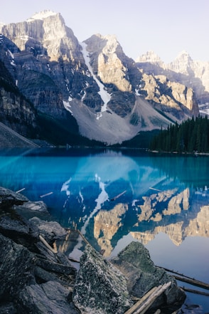 lake surrounded by green trees and snow covered mountains during daytime