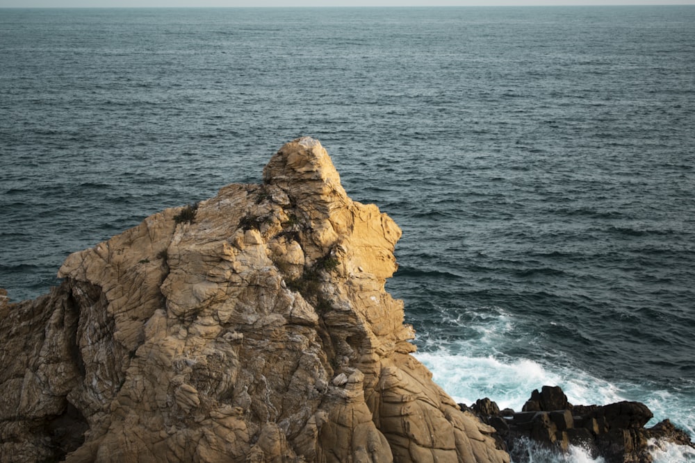 brown rock formation beside body of water during daytime