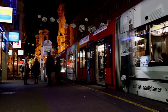 people walking on sidewalk during night time in Linz Austria