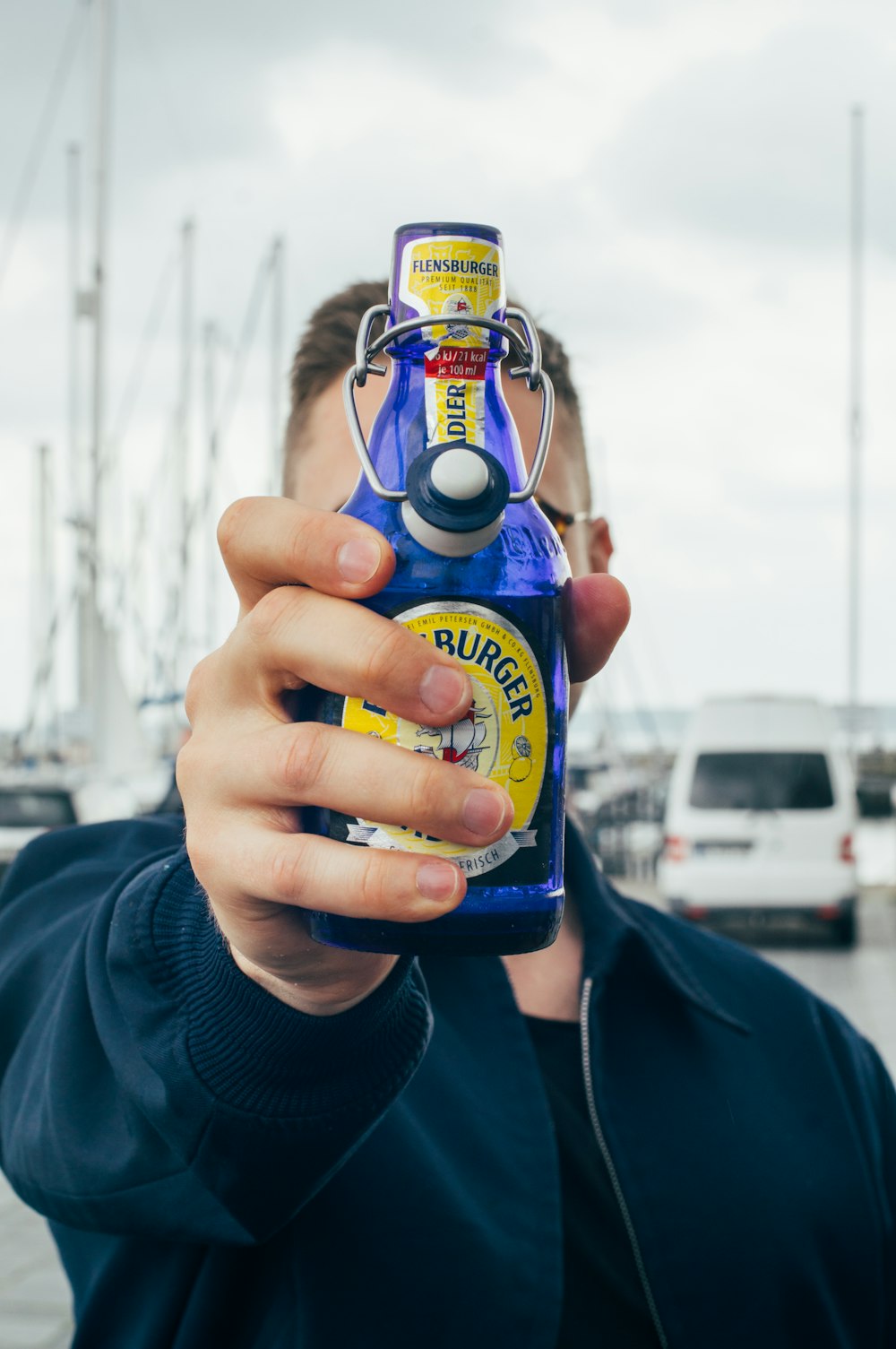 Ein Mann, der eine Flasche Bier vor sein Gesicht hält