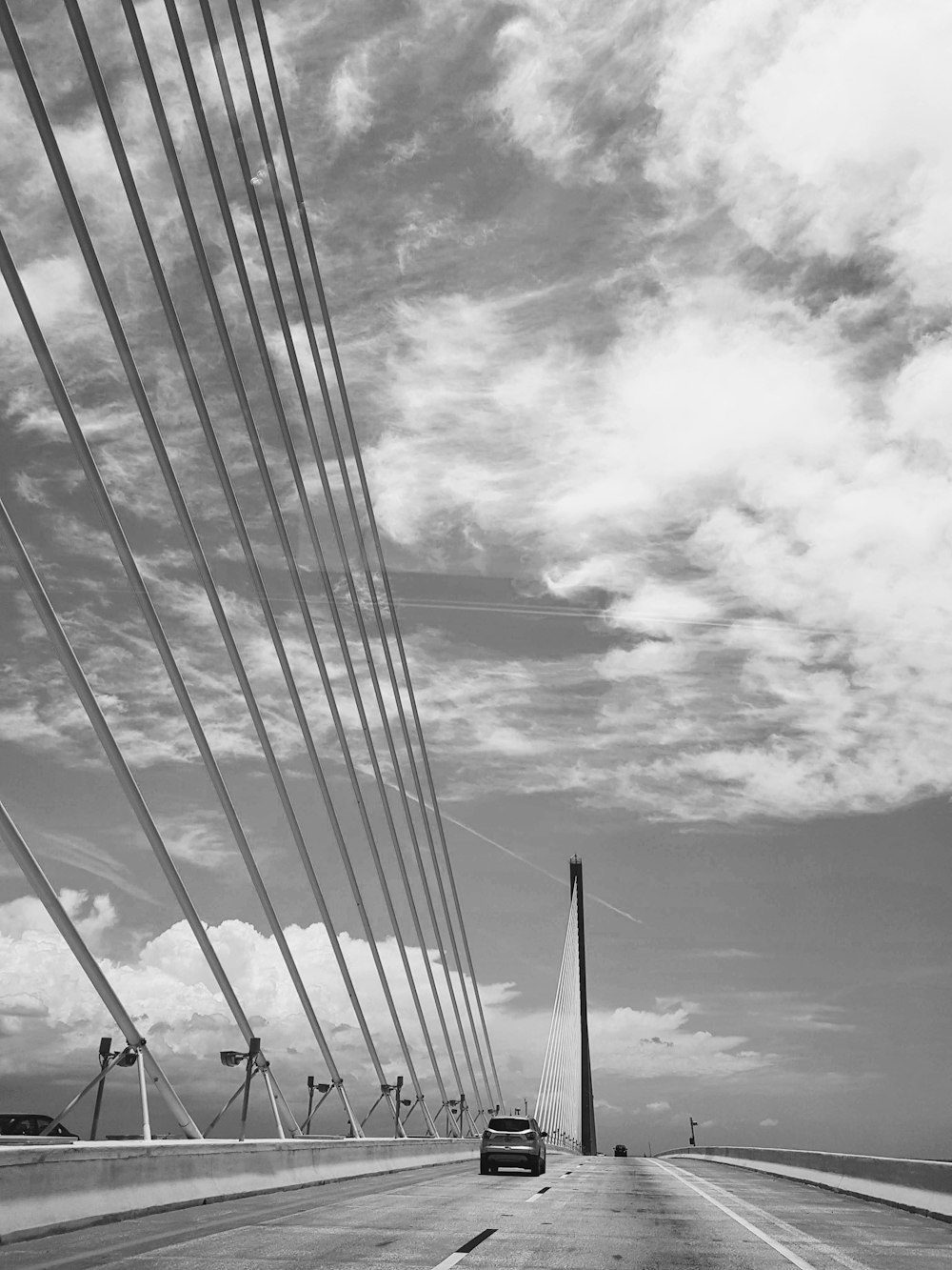 grayscale photo of electric post under cloudy sky