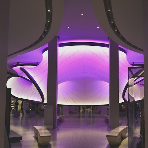 A sleek, futuristic workspace glowing with deep quantum purple and neon magenta lighting, showcasing advanced AI interfaces on transparent screens.