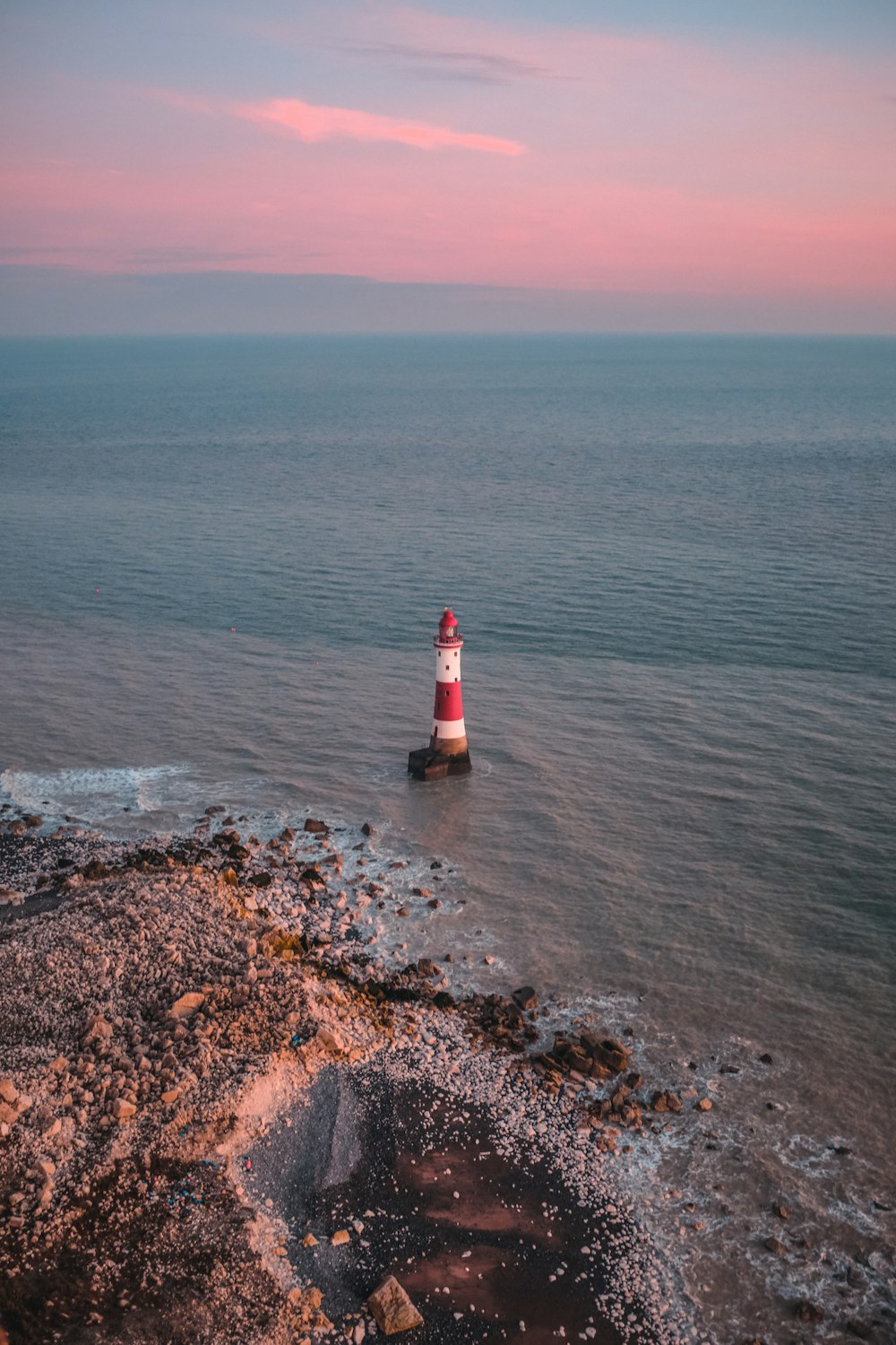 a red and white light house in the middle of the ocean