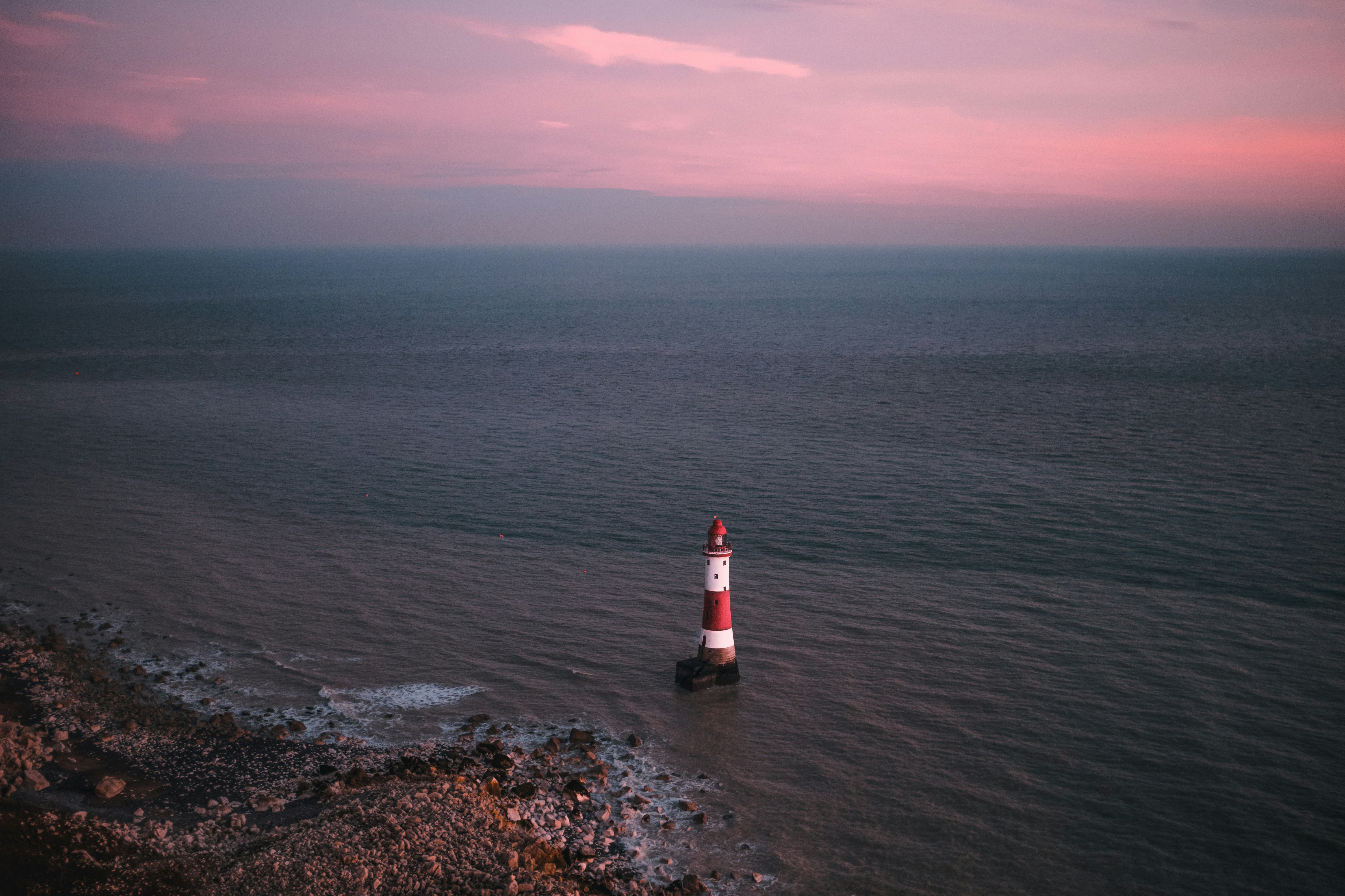 a red and white light house in the middle of the ocean, 