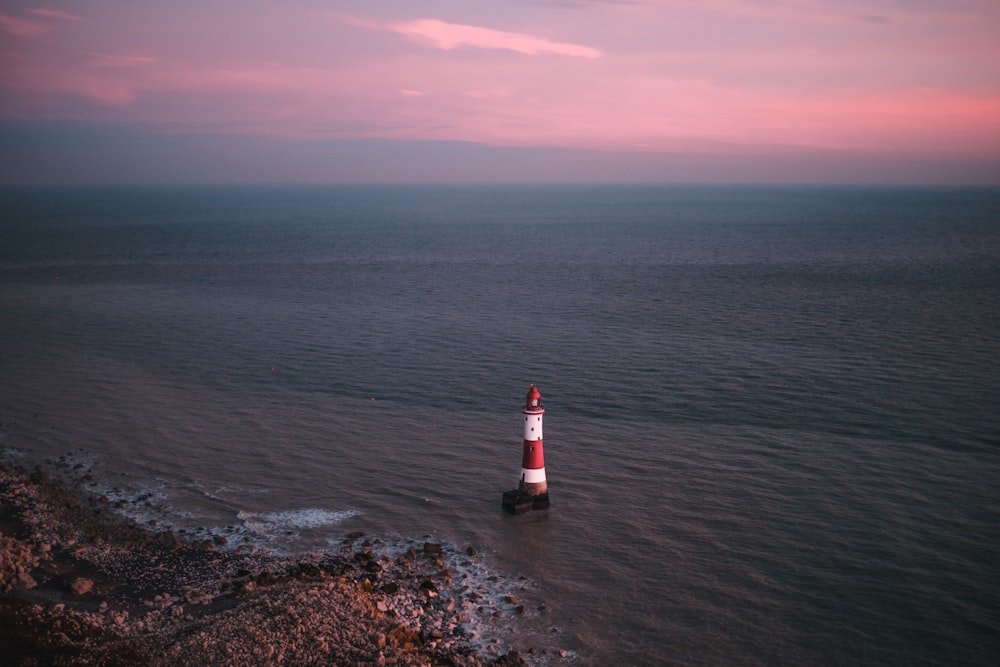 a red and white light house in the middle of the ocean