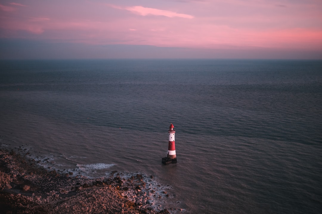 a red and white light house in the middle of the ocean,