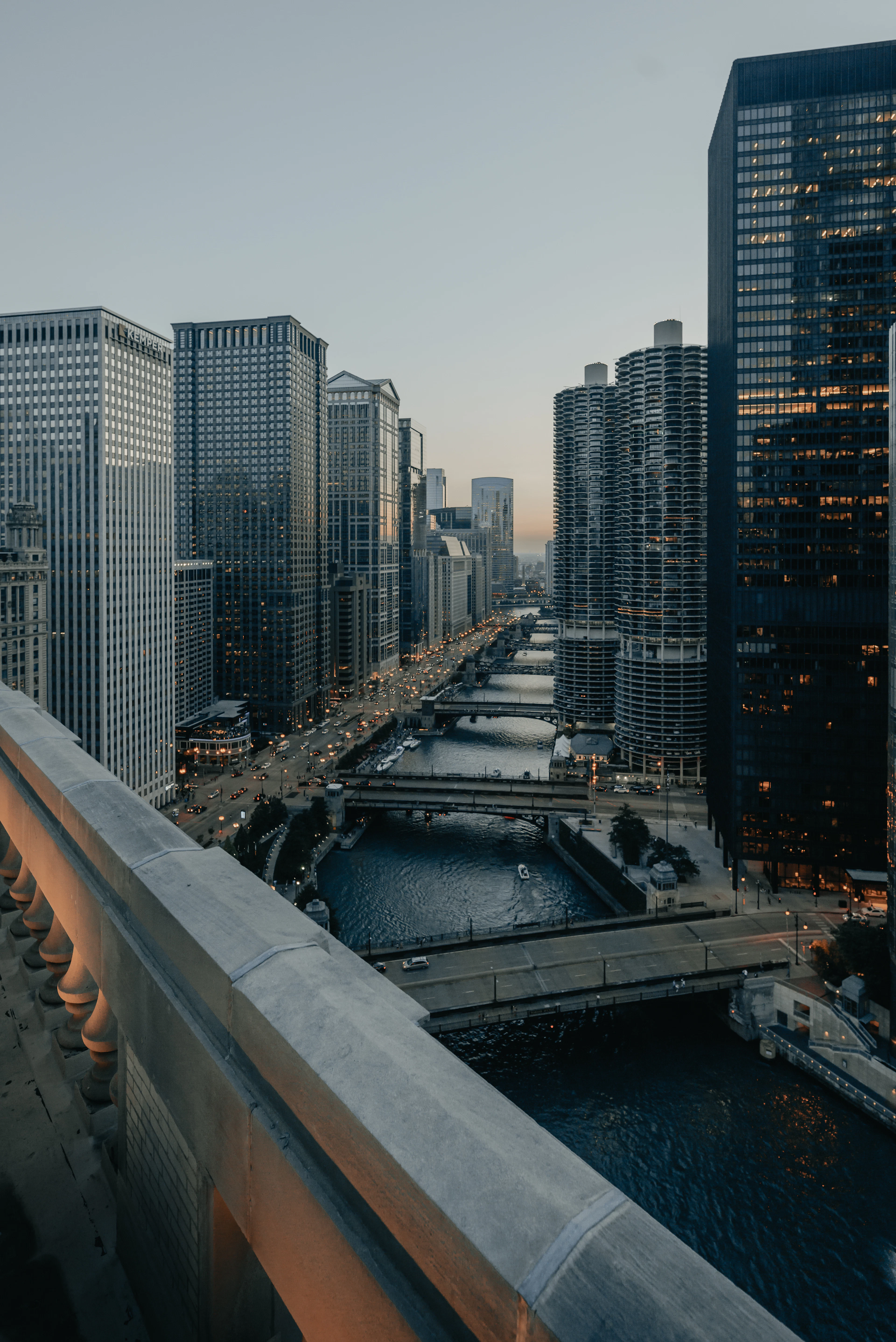 An elevated view of the Chicago River at dusk, bridges and the Marina City towers lit along its banks.
