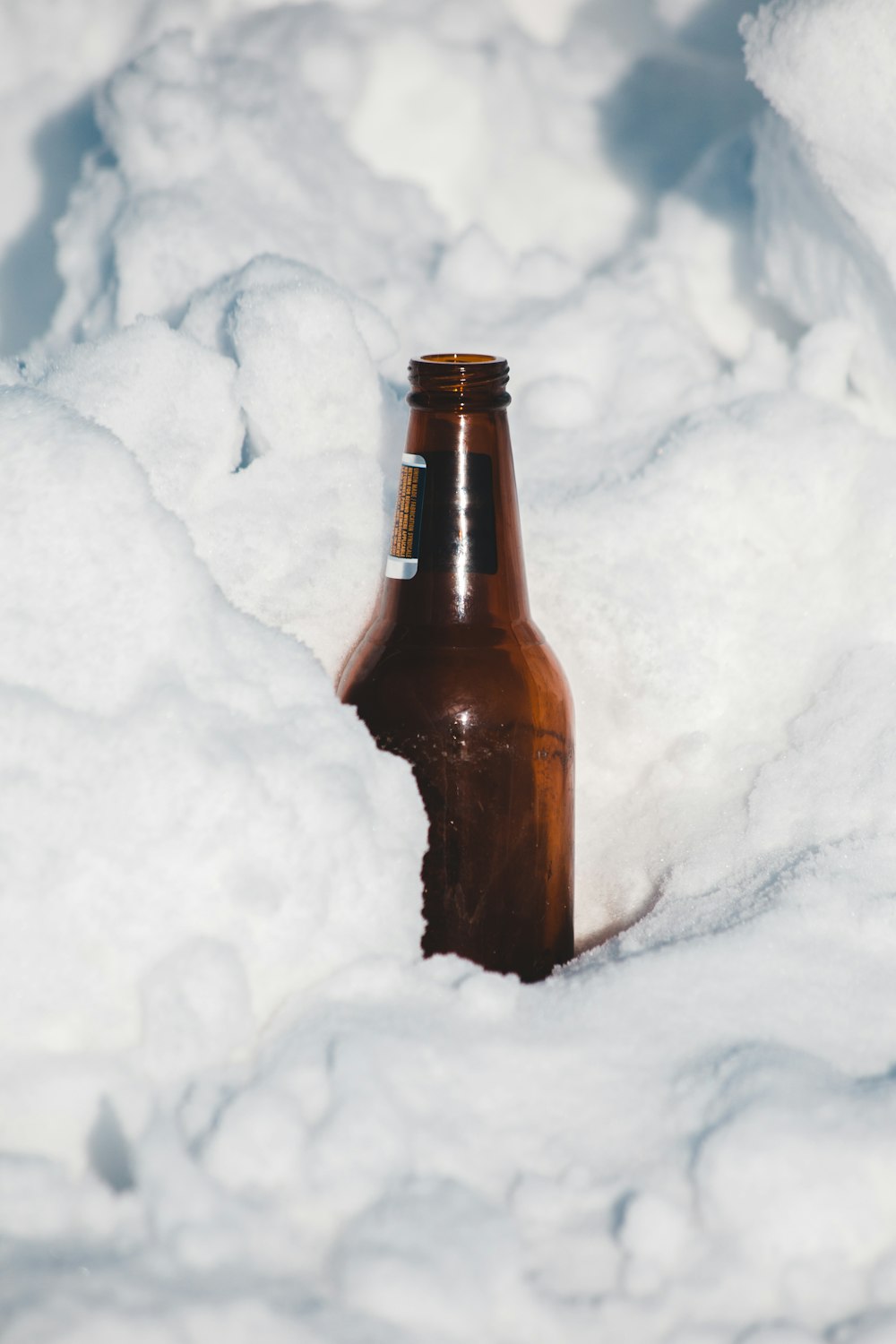 a bottle of beer sitting in the middle of a pile of snow