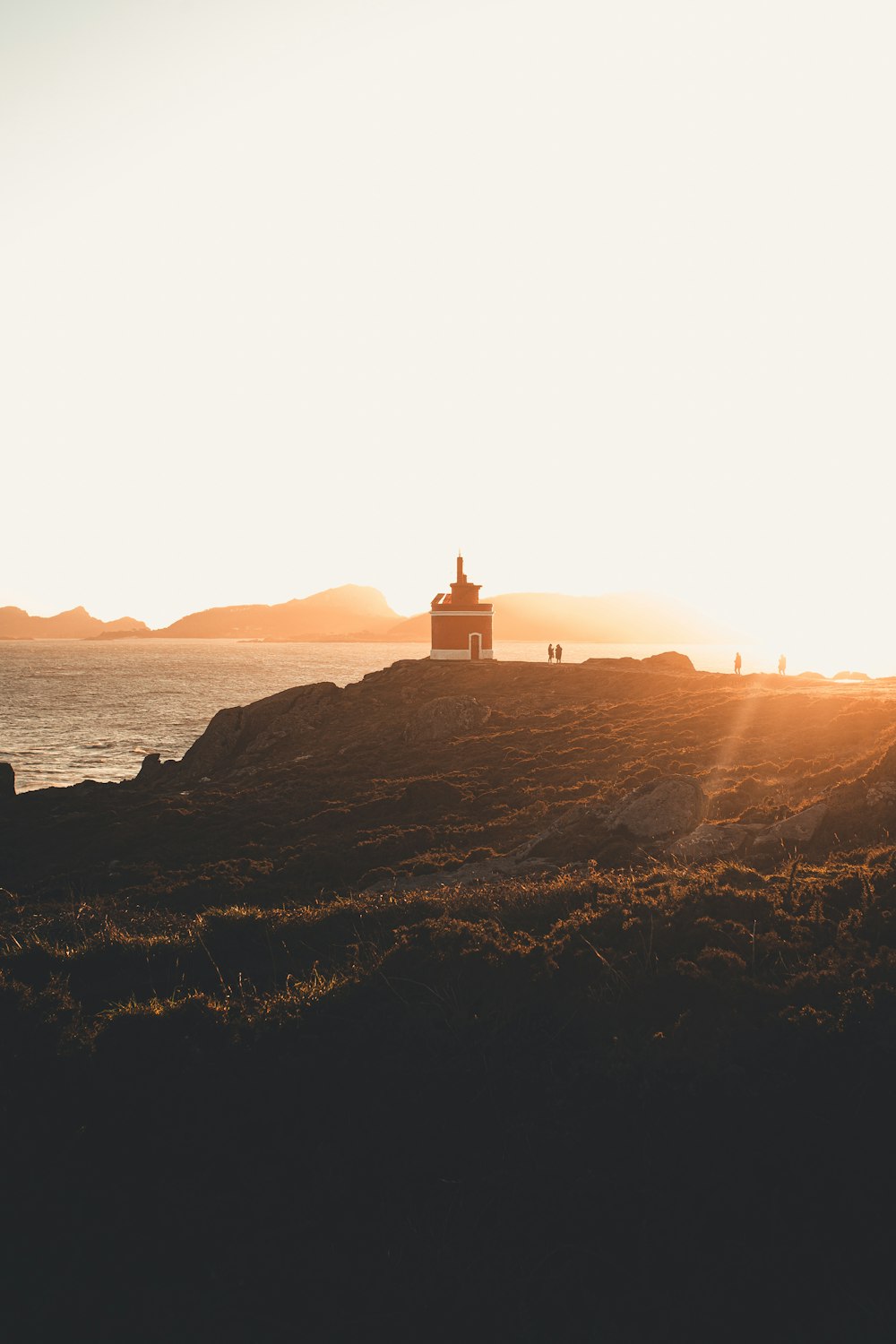 a couple of people standing on top of a hill near the ocean