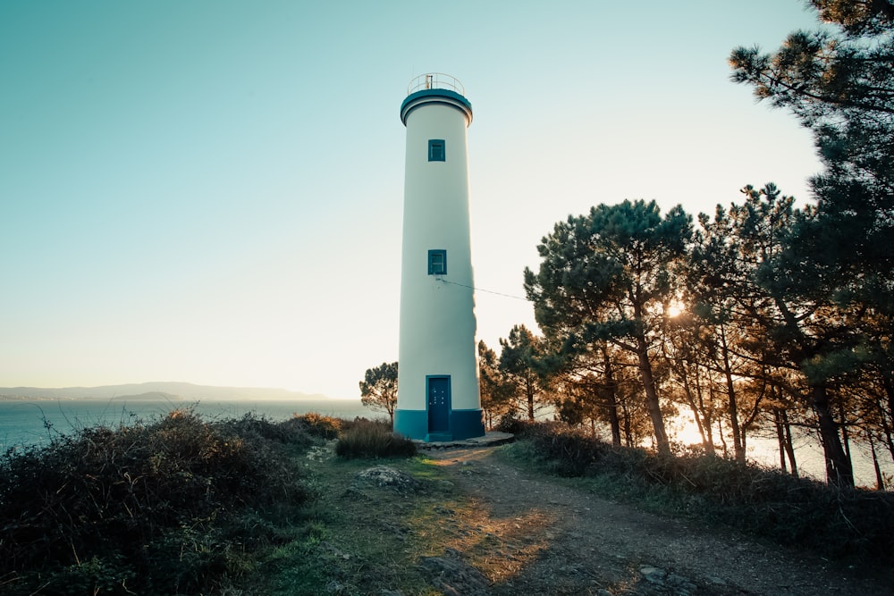 a white and blue light house sitting on top of a hill