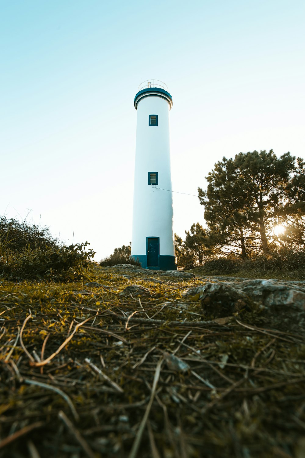 a white and blue light house sitting on top of a hill