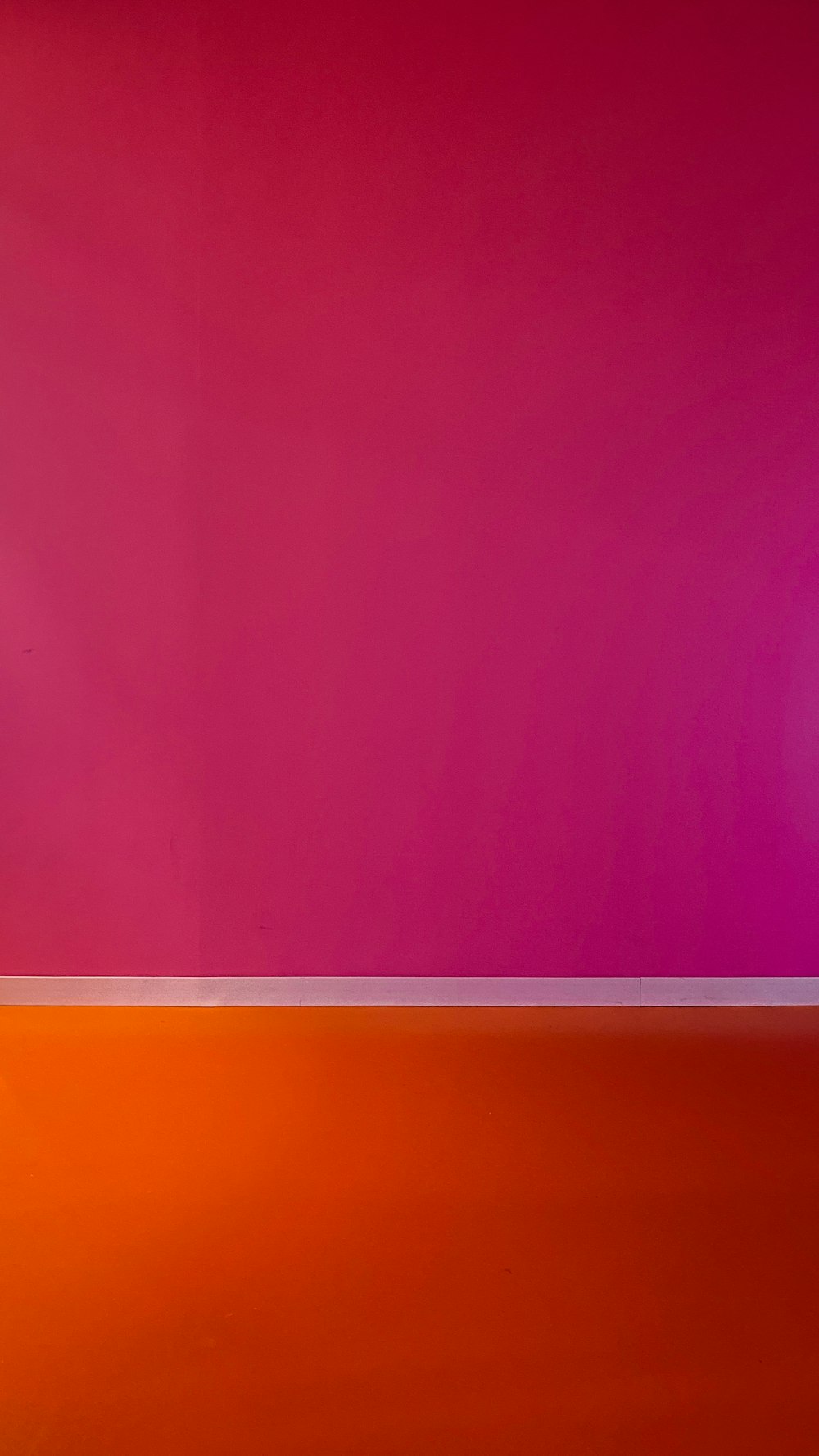 an orange and pink wall with a white floor