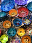 A set of decorative bowls in bold colors displayed on a rustic table.