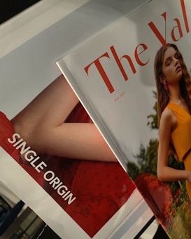 Two overlapping magazines are visible. One cover features a young woman with long hair in an outdoor setting wearing a sleeveless orange dress. The other magazine partially shown has the text 'SINGLE ORIGIN' and a red background.