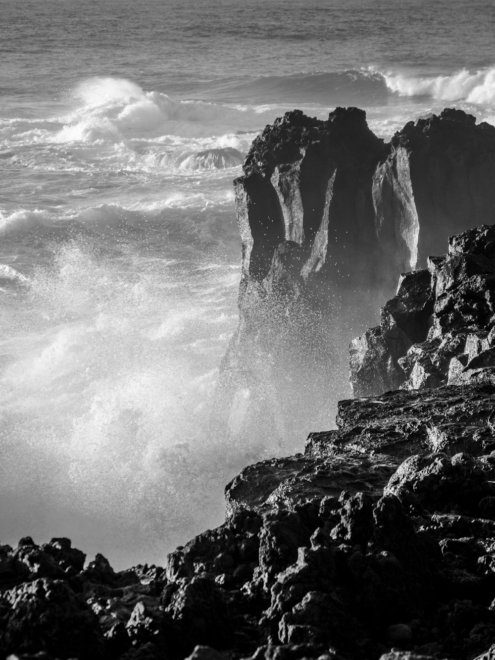 a black and white photo of waves crashing on rocks