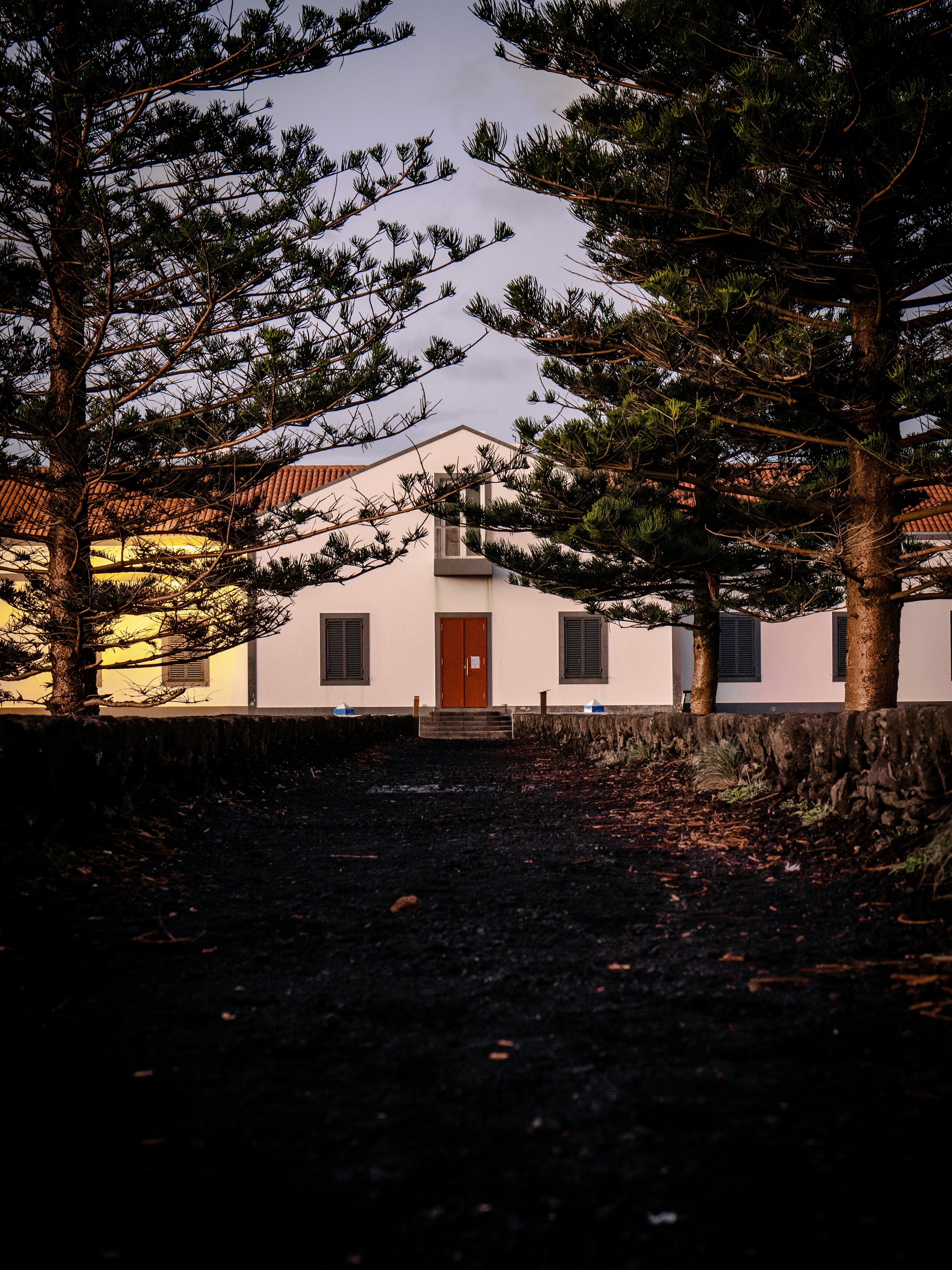 uma casa branca com uma porta vermelha cercada por árvores