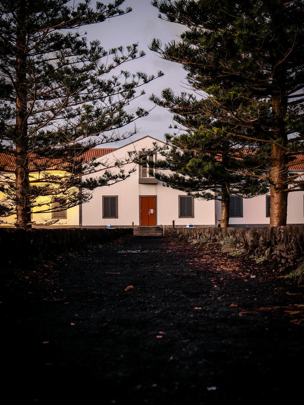 a white house with a red door surrounded by trees