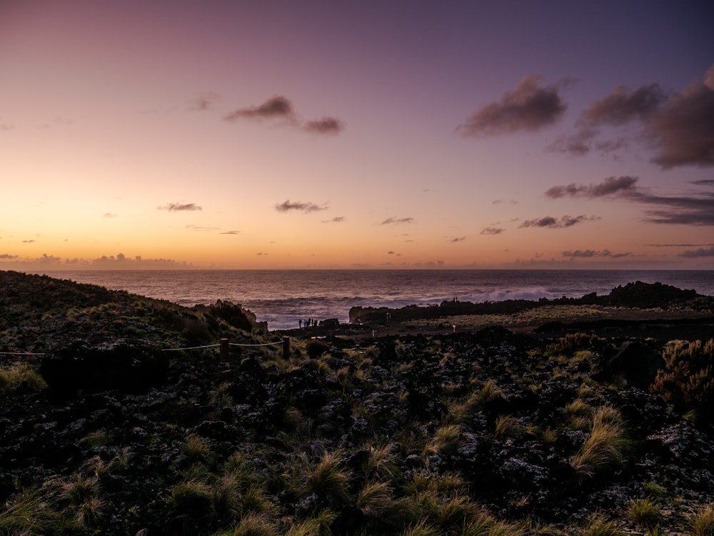 the sun is setting over the ocean on a cloudy day